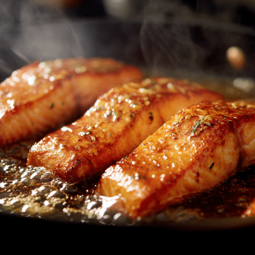 Salmon fillets sizzling in skillet with bubbling honey garlic glaze